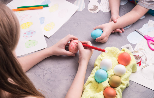 Preparing for the celebration of Easter: the girl makes a drawing on the Easter egg. - Foto, Imagem