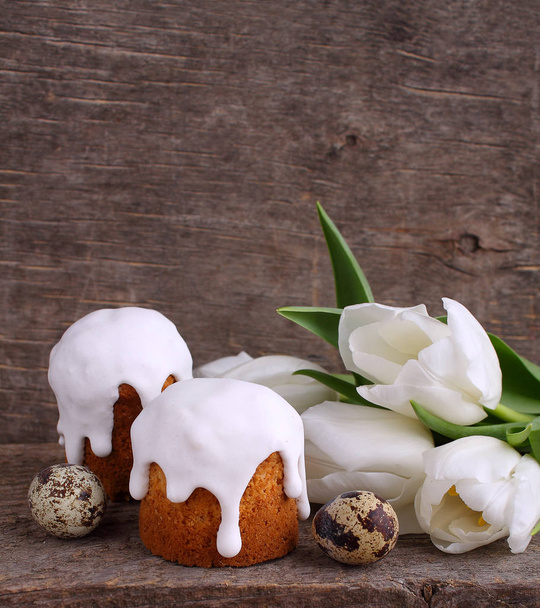 Composição de Páscoa com tulipas brancas frescas, ovos de codorna e bolos de Páscoa em fundo de madeira
 - Foto, Imagem