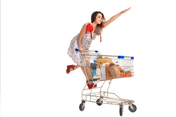 Frau mit Einkaufswagen voll mit Produkten auf weißem Hintergrund - Foto, Bild