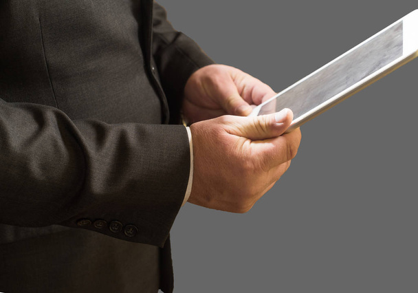 Gros plan de l'homme d'affaires debout en costume et utiliser une tablette, isolé sur fond gris
 - Photo, image