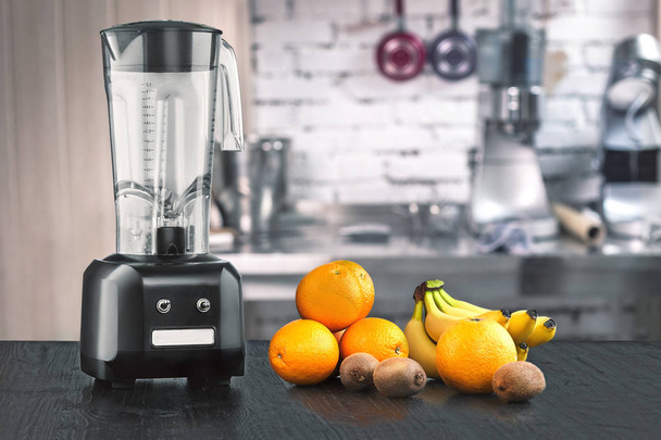 Metal food blender close-up with fresh exotic tropic fruits next to it on kitchen background with empty space - Photo, Image