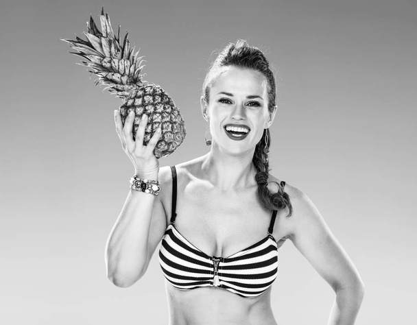 Perfect summer. Portrait of smiling healthy woman in swimsuit on the beach with pineapple - Fotografie, Obrázek