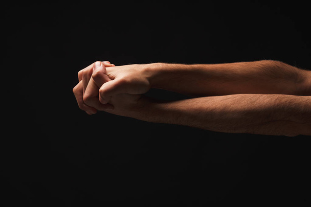 Man holding hands together at black isolated background - Photo, Image
