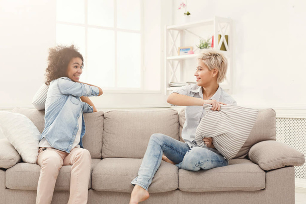 Two young women having pillow fight on sofa - Photo, Image