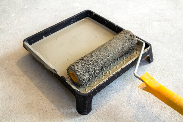 Rouleau de peinture dans le bac à peinture avec couleur grise dans le bac
 - Photo, image