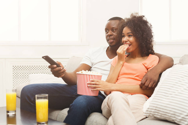 Ευτυχισμένο ζευγάρι Αφρικανικός-Αμερικανός βλέποντας τηλεόραση στο σπίτι - Φωτογραφία, εικόνα
