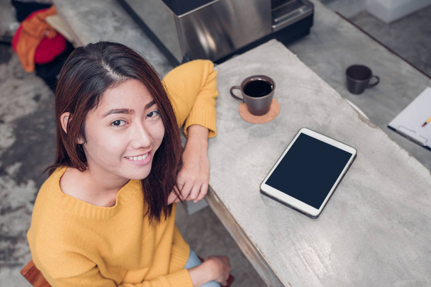 Asian woman using tablet on cafe counter bar with coffee cup and - Zdjęcie, obraz