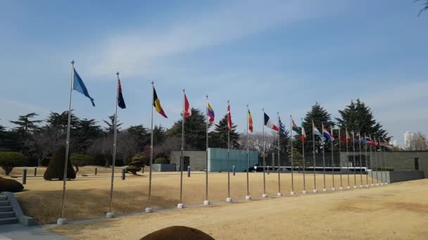 Nationale vlaggen zwaaien in de lucht van VN-begraafplaats in Busan, Zuid Korea, Azië / nationale vlaggen zwaaien in de lucht van VN-begraafplaats in Busan, Zuid Korea, Azië als Feb-22-2018. De VN-Memorial Cemetery in Korea eert VN-soldaten uit 16 landen  - Video