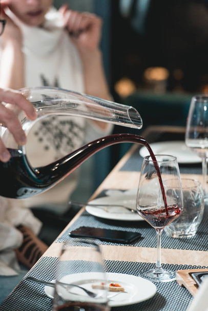 Sommelier op wijnproeverij rode wijn uit karaf gieten in glas wijn proeverij - Foto, afbeelding