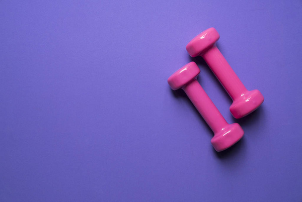 two pink dumbbell on purple background, sport and healthy concep - Photo, Image
