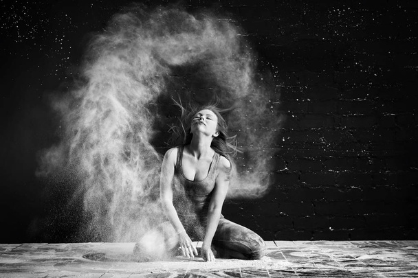 the girl in the flour makes the stroke with the hair, raising a cloud of dust - Foto, Bild