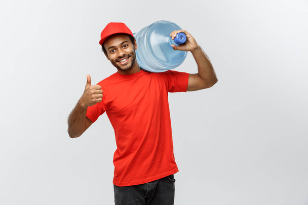 Doručení koncept - hezký afroamerické doručovatel zásobník vody. Izolované na šedé studio pozadí. Kopírovat prostor. - Fotografie, Obrázek
