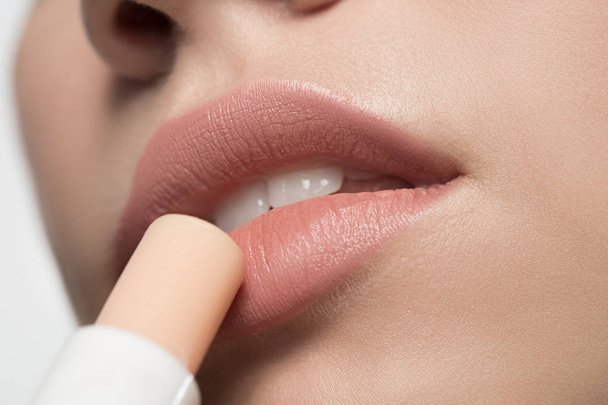 Charming young woman is using hypoallergenic balm for lips - Fotoğraf, Görsel