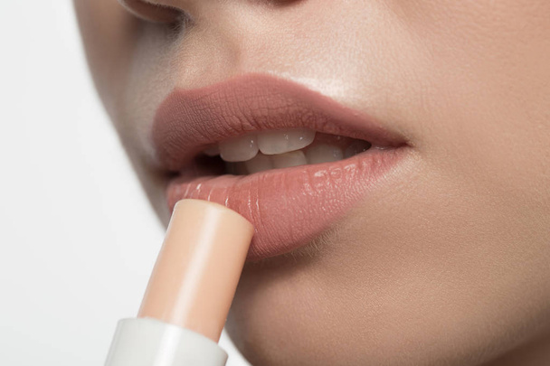 Pensive young woman is using hygienic lipstick - Valokuva, kuva