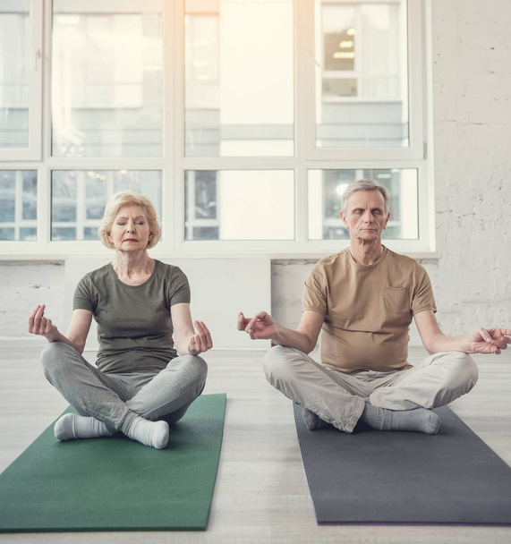 Konzentrierte Rentner meditieren gemeinsam im Studio - Foto, Bild