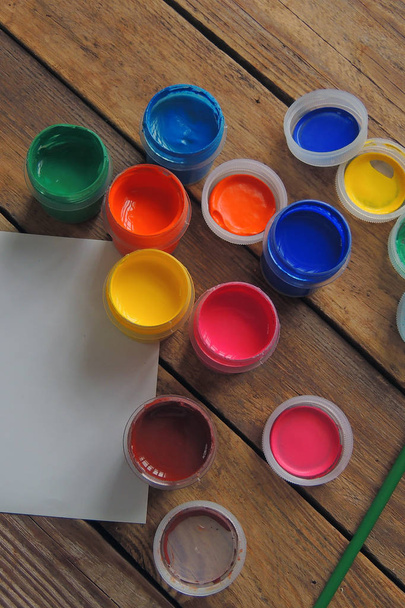 set van negen kleuren gouache-verf in potten op houten tafel. Focus op rood  - Foto, afbeelding