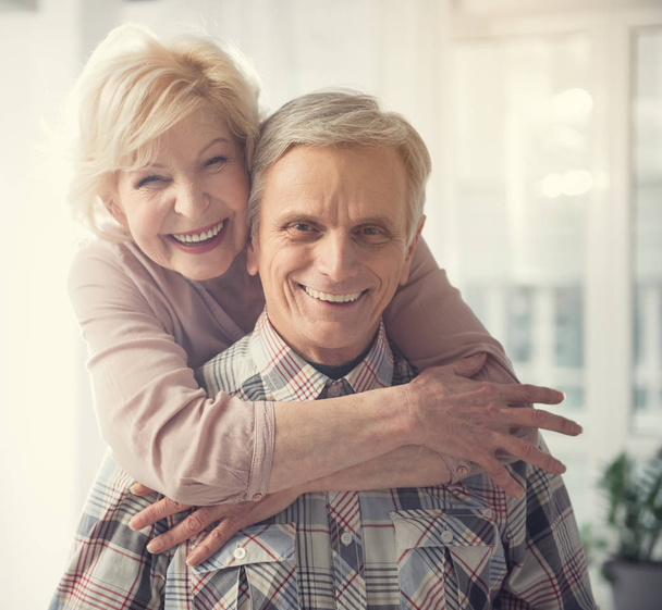 Glad mature couple standing in embrace - Фото, изображение