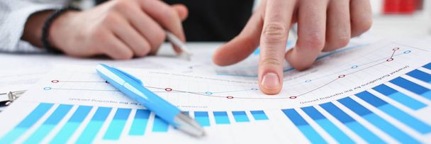 Braccio maschile in argento penna e punta dito nel grafico finanziario
 - Foto, immagini