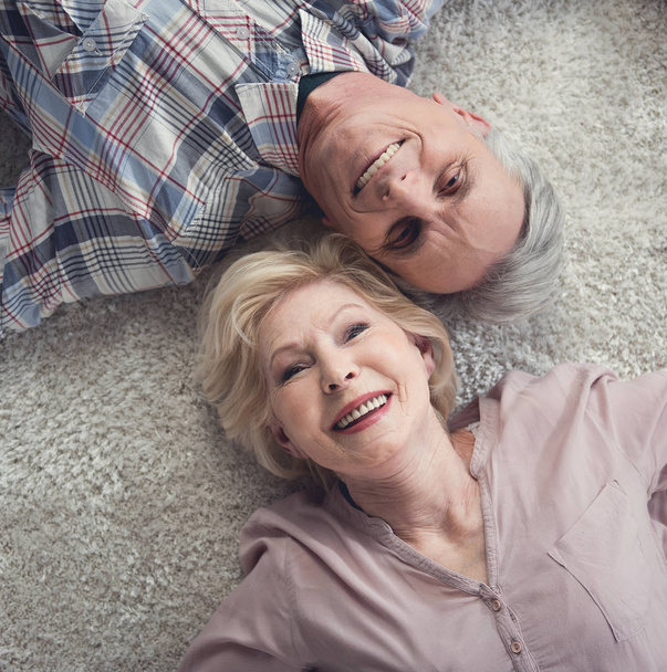 Content pensioners relaxing on carpet - Фото, изображение