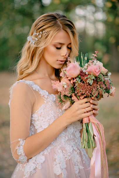 beautiful bride stands with a bouquet in hands on a nature background - Foto, immagini