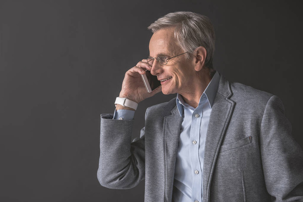 Cheerful mature male speaking by phone - Photo, image