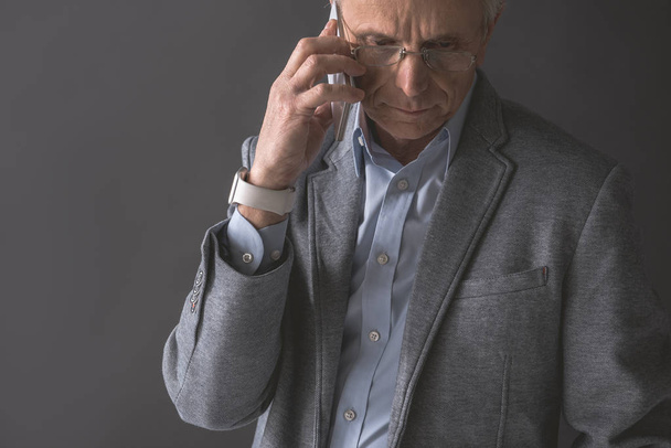 Calm old businessman talking by mobile - Foto, Bild