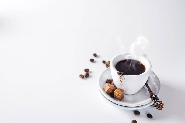 tasse de café noir sur une soucoupe avec du sucre brun sur fond blanc
 - Photo, image