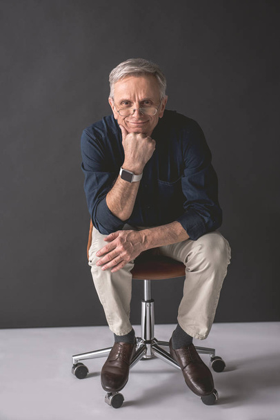 Cheerful mature male sitting on chair - Foto, Imagen