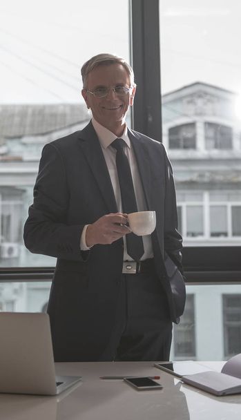 Cheerful retire businessman drinking mug of beverage - Zdjęcie, obraz