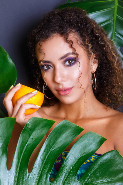 Close-up of beautiful girl posing in tropical forest. Portrait of beautiful African American woman with tropical fruits - Fotografie, Obrázek