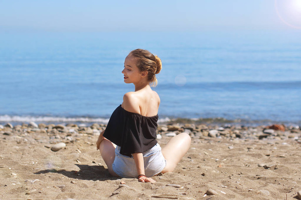 Young woman makes meditation on sea / ocean beach, harmony and contemplation. Beautiful girl practicing yoga at sea resort at her vacation. Life style. Young woman relaxing outdoors. Sun, vacation. - Foto, imagen