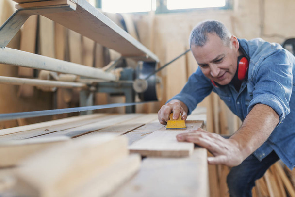 Senior man doing woodwork in carpentry. - Фото, зображення
