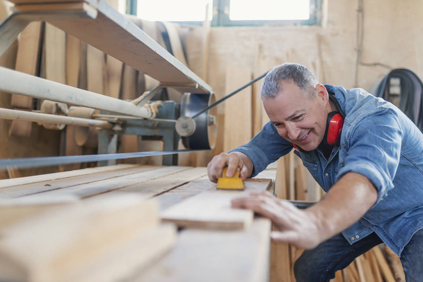 Senior man doing woodwork in carpentry. - Фото, зображення