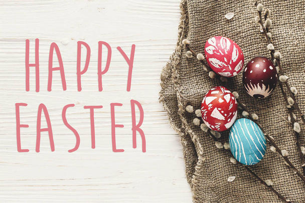 happy easter text. season's greetings card. stylish Easter flat lay. painted eggs on rustic wooden background with spring willow branches.  modern colorful eggs - Foto, immagini