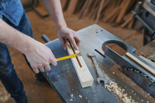 Carpenter with ruler measuring wood plank at workshop. - Foto, afbeelding