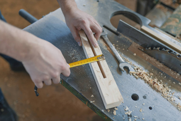 Carpenter with ruler measuring wood plank at workshop. - Foto, immagini