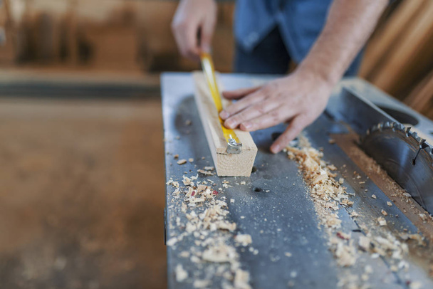 Carpenter with ruler measuring wood plank at workshop. - Foto, Imagem