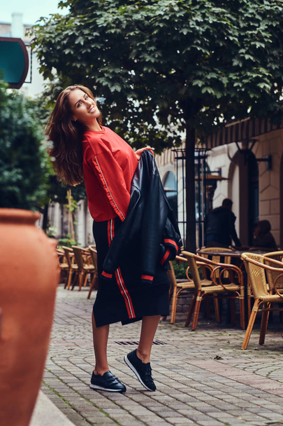 Módní brunetka v stylové oblečení má zábavu nedaleko kavárny - Fotografie, Obrázek