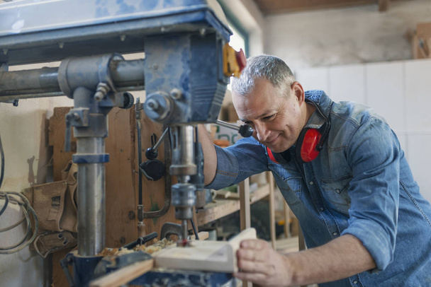 Homem engenheiro ficar perto de máquina de serra para fazer móveis na oficina carpinteiros. Negócios artesanais em pequena fábrica de móveis
. - Foto, Imagem
