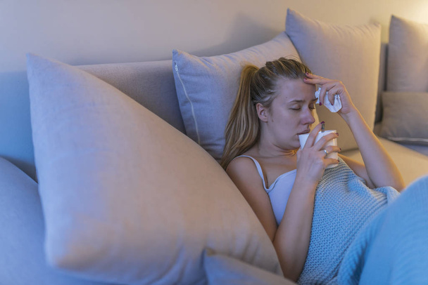 Upset young woman suffering from influenza at home and drinking tea during fever.  - Foto, imagen