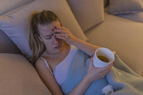 Upset young woman suffering from influenza at home and drinking tea during fever.  - Φωτογραφία, εικόνα
