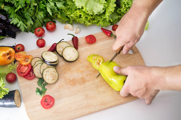 uomo affettare verdure fresche e verdure con coltello su boa di legno
 - Foto, immagini