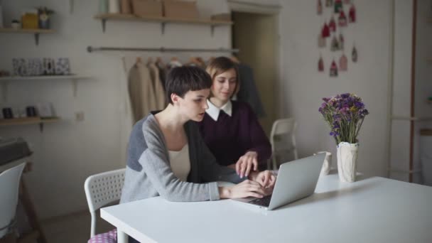 Two young woman sitting at table and using notebook. Woman working on laptop - Filmmaterial, Video