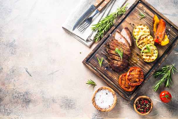 Barbecue dish. Beef steak and grilled vegetables top view. - 写真・画像