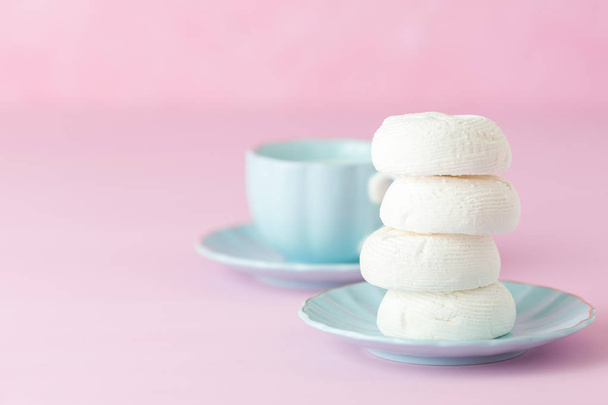 Bandiera orizzontale rosa pastello con spazio copia - dessert zephyr bianco su piatto blu e tazza di caffè con latte
. - Foto, immagini