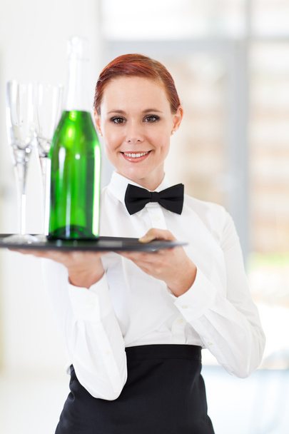 Fiatal pincérnő gazdaság egy tálca, pezsgővel és szemüveg - Fotó, kép