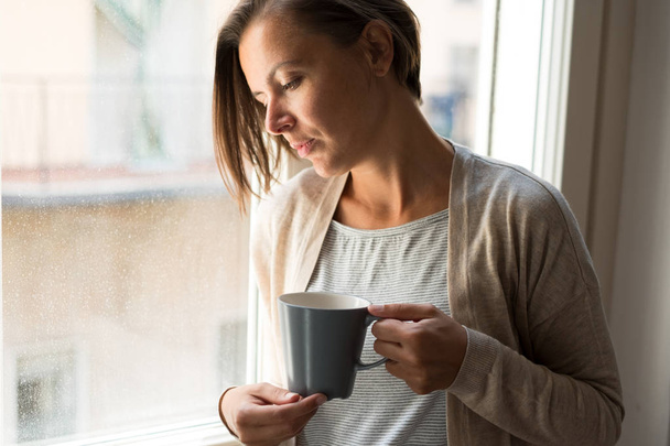 Triste mujer pensativa sosteniendo una taza de café retrato al lado de una victoria
 - Foto, imagen