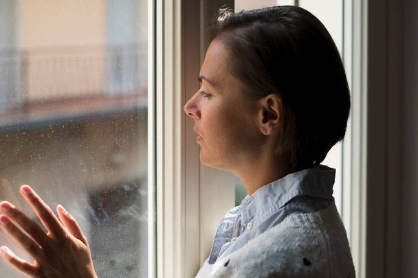 Epätoivoinen ja surullinen nainen muotokuva ikkunan vieressä
 - Valokuva, kuva
