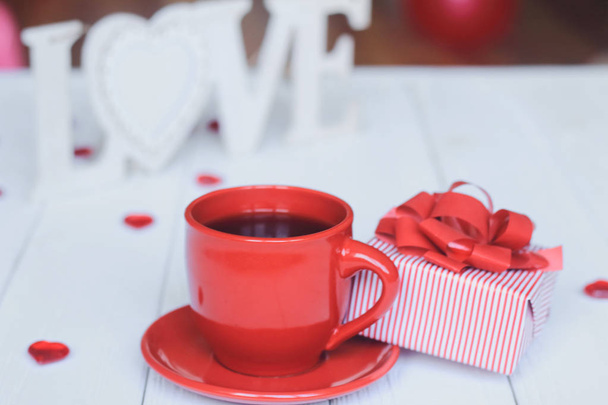 Cup of coffee and gift on blurred background. - Fotografie, Obrázek
