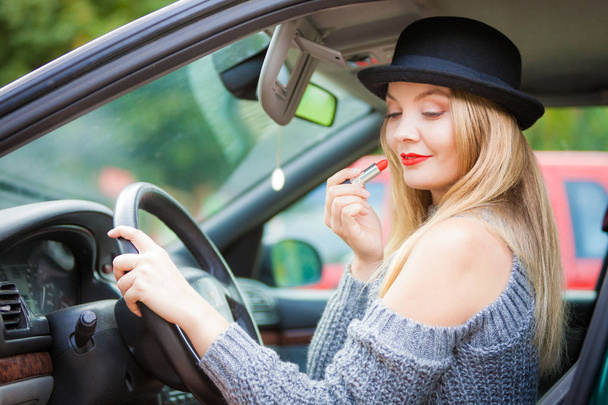 Young woman applying lipstick in car - Фото, зображення